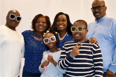 Family of 6 people posing for photo with sons focus off camera